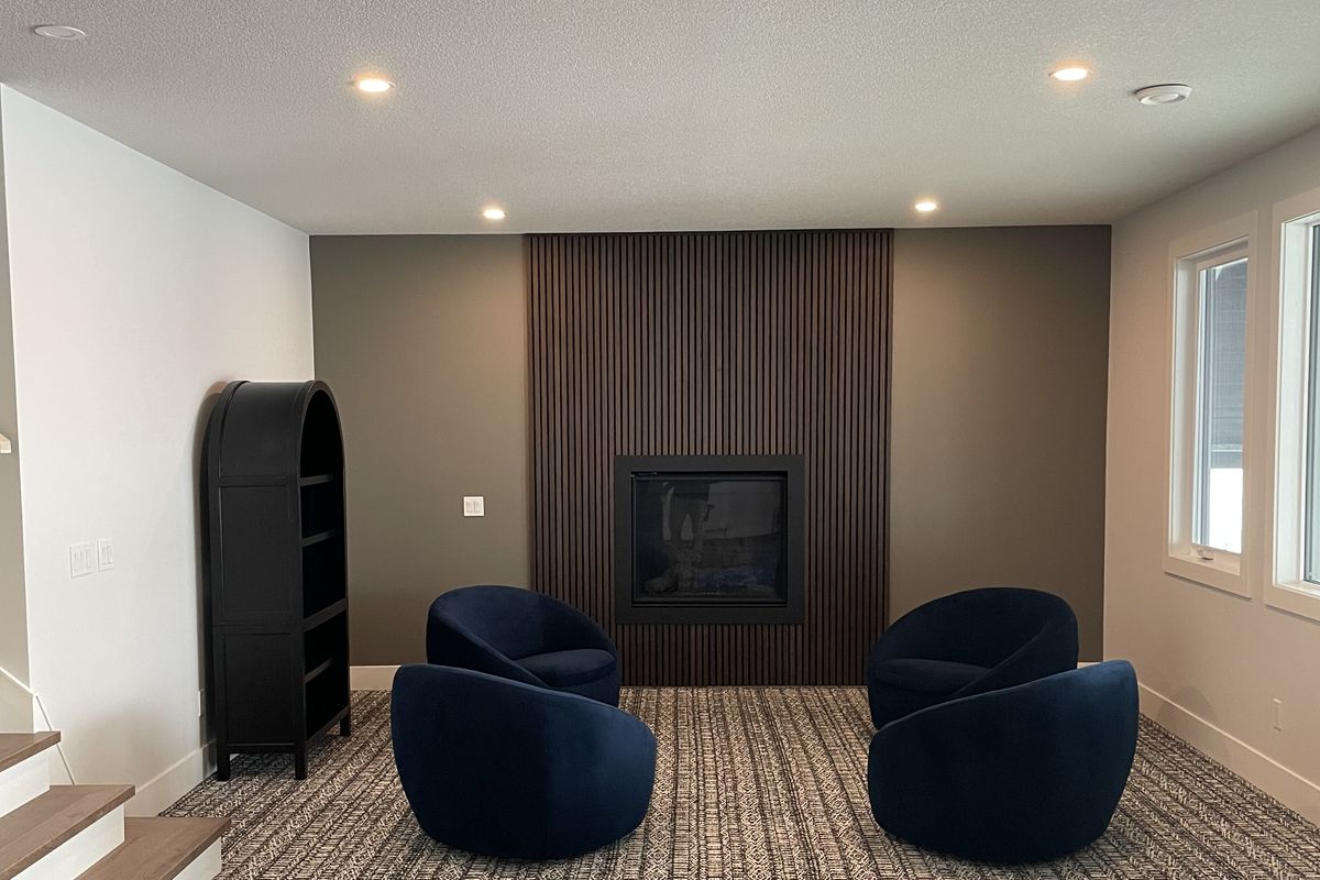 Finished basement lounge with slat fireplace and pot lighting