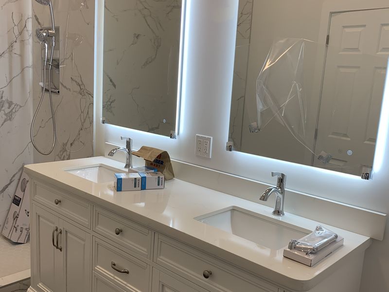 Backlit LED vanity mirrors in a marble bathroom